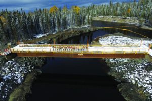 A group of workers gather on a bridge celebrating the successful construction of Peter Sutherland Sr. hydroelectric station.